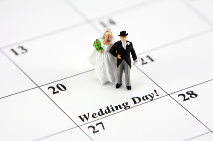 Concept image of a bride and groom standing on a calendar date that says Wedding Day.